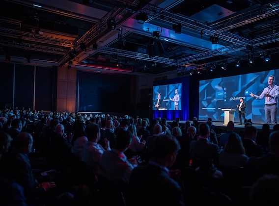 Speaker addressing a large audience at a corporate event